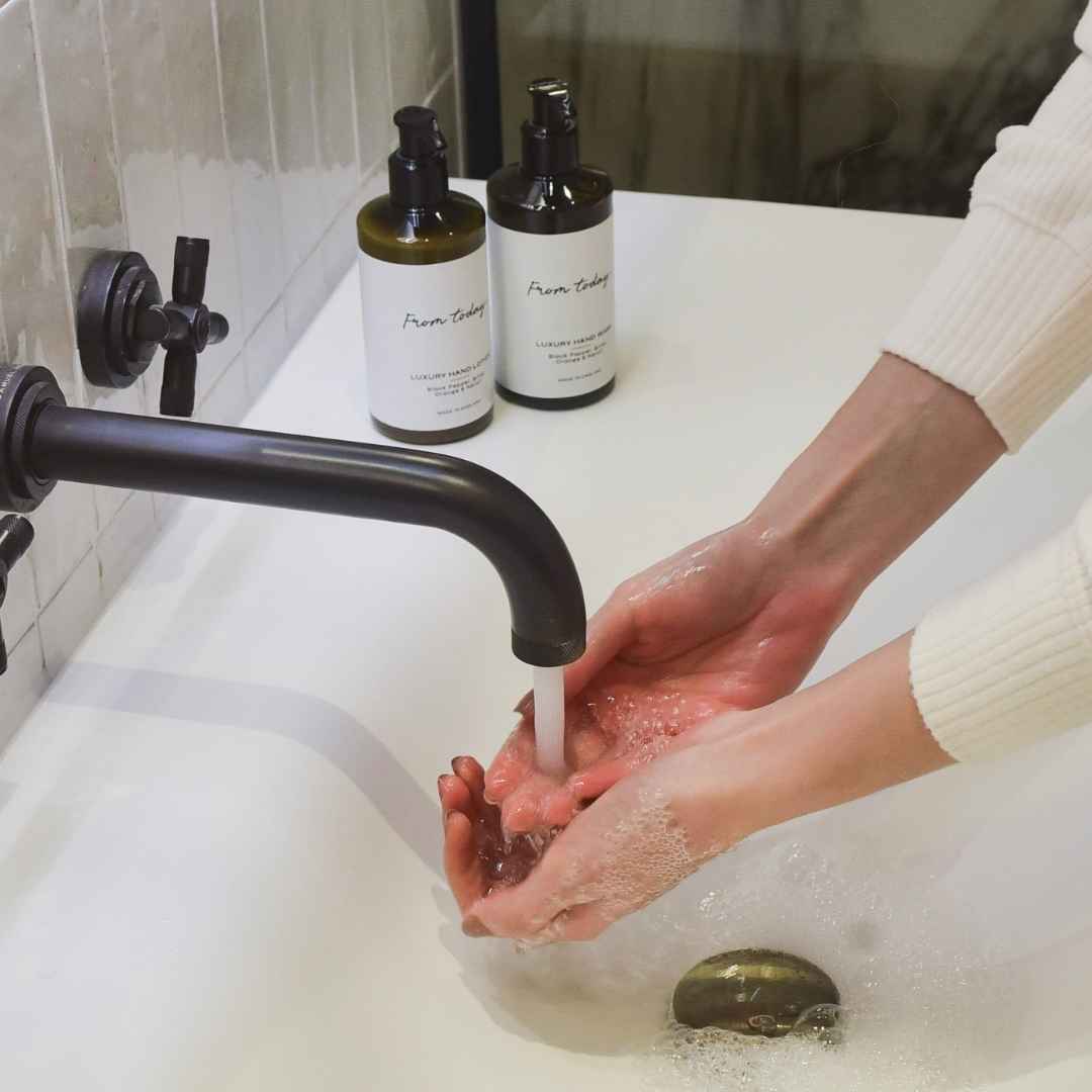 woman washing hands with luxury Black Pepper Bitter Orange & Neroli hand wash