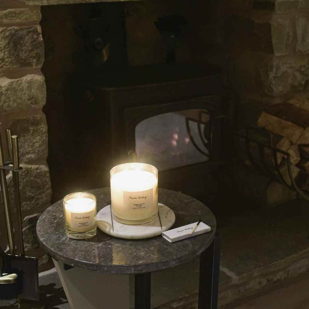 bergamot, fog & ginger 1 wick 200g candle and 3 wick 740g candle in front of cosy fireplace